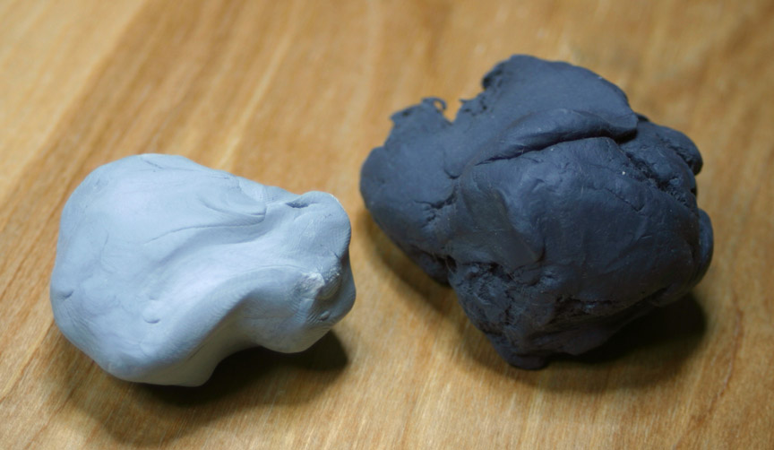 Two kneaded erasers. A newer eraser is on the left, and an older eraser on the right. The older eraser is darker due to the graphite and charcoal dust that has become incorporated into the eraser.