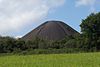 Large conical black mound with trees in the foreground