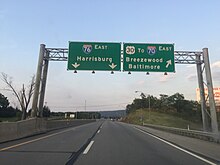 Two lanes of a four-lane highway, with two overhead signs