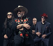 The four members of the country music band the Mavericks, against a dark blue background