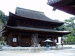 Large wooden building with a hip-and-gable roof and an enclosing pent roof.