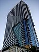 Ground-level view of a 47-story building with a rectangular cross section and a grooved, all-glass facade