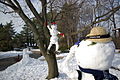 A snowman taking a photo of another snowman in a tree