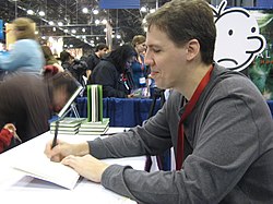 Kinney signs copies of Diary of a Wimpy Kid during a personal appearance at the booth of publisher Harry Abrams during the 2009 New York Comic Con