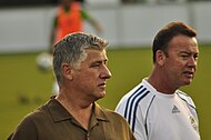 Two men with a footballer warming up behind them