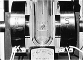 A tin cylinder—in a Dewar flask filled with liquid helium—has been placed between the poles of an electromagnet. The magnetic field is about 8 milliteslas (80 G).