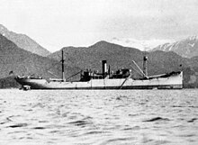 Side view of a ship upon water, with mountains visible in the background