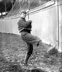 A black and white photograph of a baseball pitcher beginning his windup