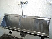 A stainless steel trough-style urinal