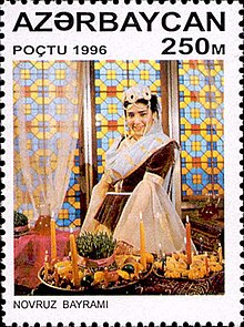 Novruz commemorative stamp, depicting a woman at a holiday table lit with candles