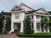 A multi-story white building stands with a small front garden