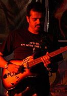 An Indian man playing a guitar.