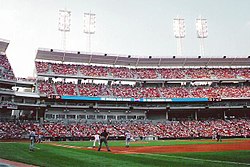 A baseball stadium with blue seats and buildings visible in the background.