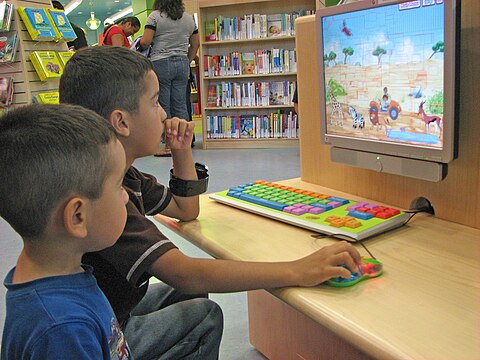 Two boys playing a computer game at a public library (2018)