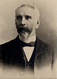 A black-and-white photograph of a man in a suit with a bow tie