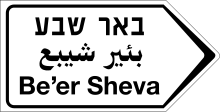 A road sign with three lines of black text on white background, each with the name "Be'er Sheva" in a different language (from the top) – Hebrew, Arabic, and English.