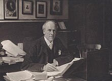 Man seated at his desk looking up at the camera