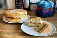 Two tier Victoria sandwich cake with a filling of strawberry jam. Two slices have been taken ready to serve, and demonstrate the cake’s construction.