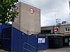 A grey building with a sign on it depicting a blue rectangle superimposed on a white circle superimposed on a red circle