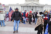 A QAnon emblem (upper left) is raised during the 2021 Capitol attack.