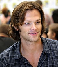 A smiling Caucasian man with long brown hair.