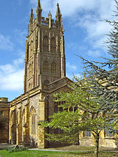 Yellow stone building with arched windows and ornate square tower.