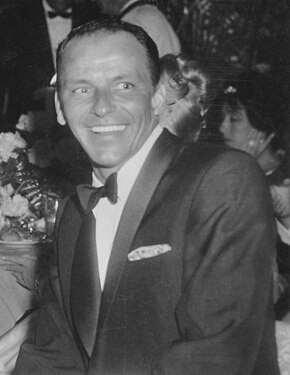 The singer Frank Sinatra in a tuxedo in a formal dinner setting