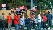 A crowd is gathered, holding placards