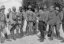 Soldiers wearing nine distinct uniforms stand in a circle.