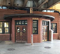 A front-bayed brick building with darker bricks, simpler styling, and dark wood doors