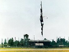 A B-52 in flight, rolled 90° to the left, very close to the ground and pointing towards it.