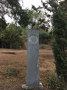 A slate pillar, with Papadimitriou's portrait in profile, his name and a short epitaph carved in Greek.