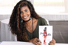 Nic Stone sits at a table while holding a copy of her book, Dear Martin, in 2017.