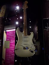 A color photograph of a white Fender Stratocaster guitar