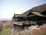 Wooden building with large hipped roof constructed on long poles.