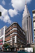 In the foreground: the abandoned Yoyogi Kaikan [ja] building that appears in the film. The demolition of the building was completed in January 2020 and it no longer exists.[136] Note that the rooftop shrine in this film is fictional. Back: the NTT DoCoMo Yoyogi Building (Docomo Tower), which frequently appears in Shinkai's films.