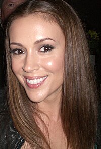 A close-up of a light-skinned woman with long brown hair swept over her shoulder; she is seen smiling.