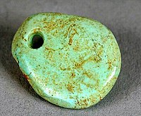 A small oval pieced of turquois with a hole drilled though the top