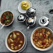 A Tibetan meal with (clockwise from top) tingmo (steamed bread), thenthuk (noodle soup), momos in soup, vegetable gravy, and condiments in center from the Himalaya Restaurant.