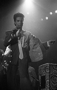 A black and white photo of Prince singing onstage