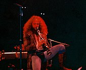 Jethro Tull leader Ian Anderson, wearing a codpiece and tights, stands on one leg as he plays a soprano saxophone