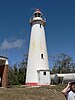 A lighthouse with a gallery and a lantern painted white with a red dome