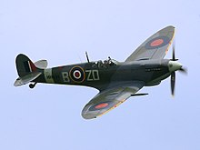 A Spitfire with RAF markings, flying against a blue sky