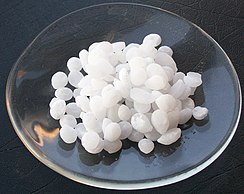 Sample of sodium hydroxide monohydrate as pellets in a watchglass