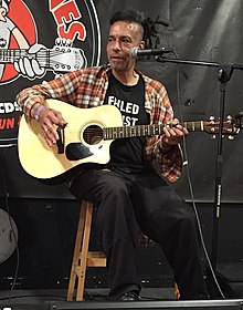 Mosley pictured in 2016, playing an acoustic guitar