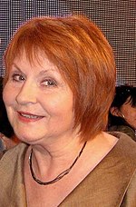 Close-up of Jędryka with red hair, smiling at the camera.