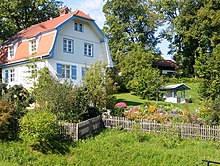 White, two-story home with attic and a garden