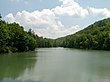 A reservoir flanked by green forested hillsides on either side and in the background.