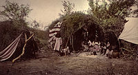 Chiricahua medicine man and family in wickiup