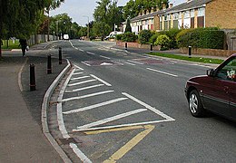 Two traffic calming measures: speed cushions (the two reddish pads in the road) and a curb extension (marked by the black posts and white stripes)